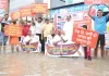 निवारू रोड पर पानी में खड़े होकर दिया धरना : सड़क पर भरा पानी, सांकेतिक नाव चलाकर किया प्रदर्शन 